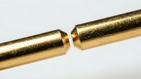 Golden metallic cylindrical objects with smooth reflective surface connecting together on neutral background for industrial design applications.