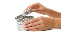 Woman's hands holding and opening a blister pack of medication tablets isolated on white background for healthcare, pharmaceutical, and medical treatment concepts.