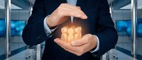 Businessman in dark suit holding glowing team of people icons between hands, representing leadership, protection, and human resources management in corporate environment.