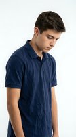 Young male teenager, Caucasian ethnicity, wearing navy blue polo shirt, looking downward with neutral expression against white background for portrait and lifestyle use.