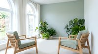 Bright minimalist living room with two wooden armchairs, sage green cushions, large arched window, and lush tropical plants against a soft green wall.