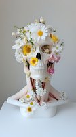 White skull adorned with fresh daisies, yellow flowers, and pink blooms arranged as artistic floral sculpture. Surreal botanical art installation for creative design projects.