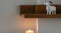 Wooden shelf with white decorative goat figurine and lit candle below, creating warm ambient lighting for home decor and interior design projects.
