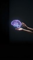 Hand holding glowing purple neural network brain hologram against dark background, representing artificial intelligence, innovation, and digital technology concepts.