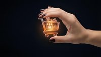 Elegant female hand holding glowing golden shopping cart against dark background, symbolizing e-commerce, online retail, and digital shopping success for business and marketing.