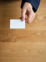 Senior Caucasian male hand holding blank white card over wooden floor, suitable for business presentations, contact information, and corporate branding mockups.