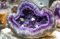Purple amethyst geode crystal formation with concentric bands of color from deep violet center to white edges, displaying natural crystalline structure and growth patterns.