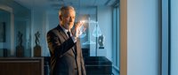 Professional mature Caucasian businessman in suit touching digital holographic interface in modern office environment for technology and innovation concepts.