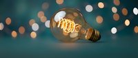 Vintage Edison bulb with glowing filament against bokeh lights background for creative lighting design and retro decor concepts.