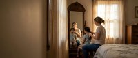Young Caucasian mother with toddler son getting ready in cozy bedroom with vintage mirror and warm natural lighting for family lifestyle content.