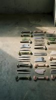 Collection of jade gua sha tools and facial massage stones arranged on concrete floor for skincare and wellness therapy treatments.