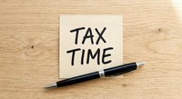 Tax time reminder note with black pen on wooden desk for financial planning and accounting preparation.