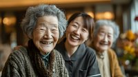 Three generations of Asian women smiling together in warm home setting, showcasing family bonds, happiness and intergenerational relationships in cozy interior.