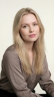 Young blonde Caucasian woman in brown blouse smiling confidently at camera in professional studio portrait for business and corporate marketing materials.