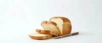 Fresh sliced white bread loaf on wooden cutting board isolated on white background for bakery and food design projects.