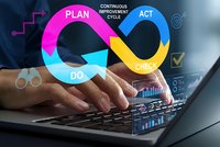 Business professional typing on laptop with colorful PDCA cycle diagram overlay showing plan do check act continuous improvement process for quality management.