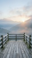 Wooden deck with railing overlooking misty mountain valley at sunrise, ideal for travel, nature, and wellness design projects.