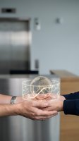 Two people holding holographic globe with network grid overlay in modern office environment, representing global business collaboration and digital connectivity.