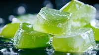 Frozen lime green jello cubes with water drops on dark background, close up macro shot with selective focus for food and beverage advertising.