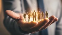 Business professional holding glowing team silhouettes in cupped hands representing leadership, human resources management and corporate teamwork concepts.