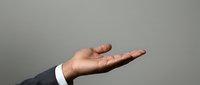 Male hand in business attire gesturing open palm upward against neutral background, conveying offering, support, or presentation for corporate communications.
