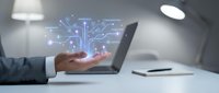 Businessman hand holding laptop displaying glowing circuit board network diagram with data flow visualization for technology, artificial intelligence, digital transformation, and business innovation concepts.