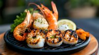 Grilled seafood platter with jumbo shrimp and seared scallops, garnished with fresh herbs and lemon on black cast iron plate, selective focus on charred marks.
