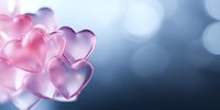 Translucent pink and purple heart shapes floating against blurred blue bokeh background create romantic atmosphere for Valentine's Day designs and love themes.