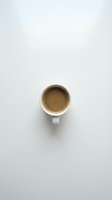 White ceramic mug filled with hot espresso coffee on neutral background, overhead view. Suitable for café, beverage, and lifestyle design projects.