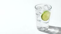 Refreshing glass of sparkling water with cucumber slice and ice cubes on white background for healthy lifestyle and hydration concepts.