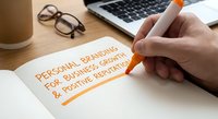 Hand writing personal branding goals for business growth and creative reputation on notebook with orange highlighter at modern workspace.