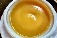 Creamy butternut squash soup served in white ceramic bowl, close-up view showing smooth texture and rich golden color. Homemade comfort food for cold weather.