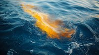 Vibrant orange oil spill floating on deep blue ocean water surface creates abstract patterns and textures, highlighting environmental pollution and ecological impact.