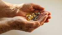 Mature male hands holding mixed dried legumes and grains including lentils and beans, representing nutrition, agriculture, and sustainable food sourcing for culinary and wellness content.
