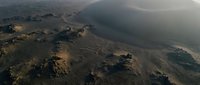 Aerial view of dramatic desert landscape with rolling hills, winding paths and atmospheric haze creating moody natural scenery for environmental projects.
