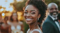 Young African American woman with natural curly hair and radiant smile wearing white lace dress at outdoor celebration during golden hour sunset.