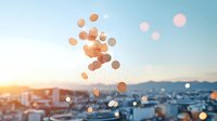 Dreamy cityscape at sunset with golden bokeh lights floating across urban skyline and mountains, creating atmospheric mood for background designs.