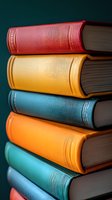 Stack of colorful hardcover books with red, yellow, blue, and orange leather bindings against dark background, perfect for education or literature themes.