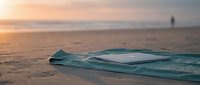 Abandoned turquoise kayak lies on sandy beach at sunset with calm ocean and distant figure in background, suitable for travel and adventure themes.