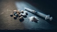 Drug addiction concept with syringe, pills and powder on dark wooden surface for awareness campaigns and educational materials.