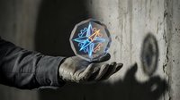 Gloved hand holding glowing geometric sphere with blue and orange light patterns against concrete wall background.