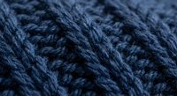 Blue knitted wool yarn texture with cable pattern stitch detail for crafting and textile design projects.