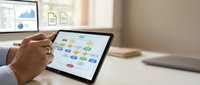 Professional businessman analyzing colorful workflow diagram on tablet device in modern office environment for business process optimization and strategic planning.