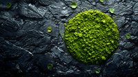 Green matcha tea powder circle on dark stone background with scattered leaves, top view composition for culinary and wellness concepts.