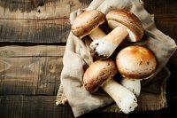 Fresh brown and white mushrooms on rustic linen cloth against dark wooden background, natural organic food photography with moody lighting.
