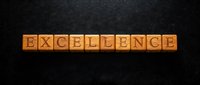 Wooden letter cubes spelling EXCELLENCE on a dark textured background, symbolizing quality, achievement, and high standards in business.