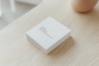 Blank white business cards stacked on light wood surface with ceramic cup, mockup for branding, corporate identity design, and stationery presentation.