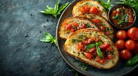 Italian bruschetta with fresh tomatoes, basil and herbs on crusty toasted bread served on rustic plate with cherry tomatoes and marinara sauce.