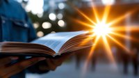 Open book with bright sunburst light effect creating inspirational atmosphere. Pages flutter in breeze against blurred outdoor background with bokeh lights.