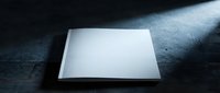 Blank white paper sheet on dark concrete surface with dramatic lighting creating shadows and highlights for mockup presentations.